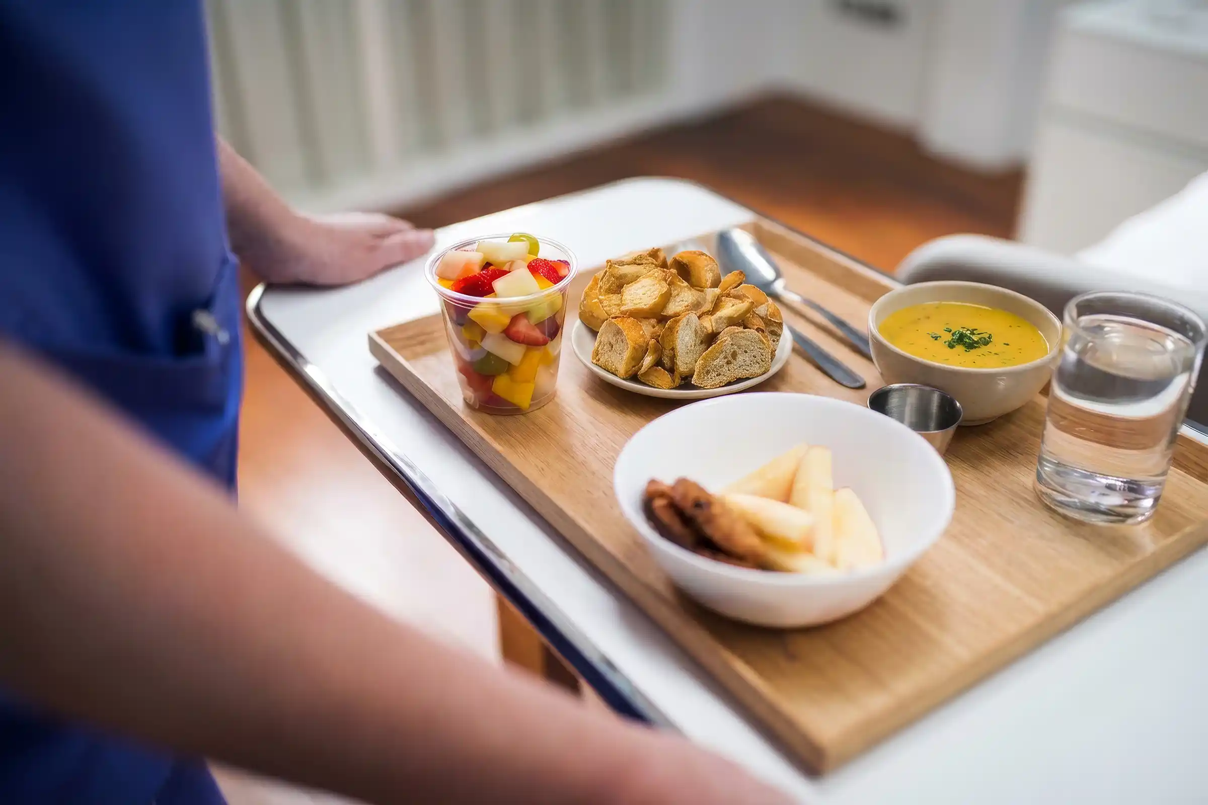 Bandeja de refeição hospitalar com sopa, frutas e torradas